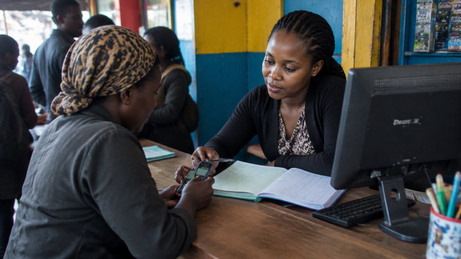 Mobile-Money-Agentin in Kampala bedient einen Kunden am Schalter