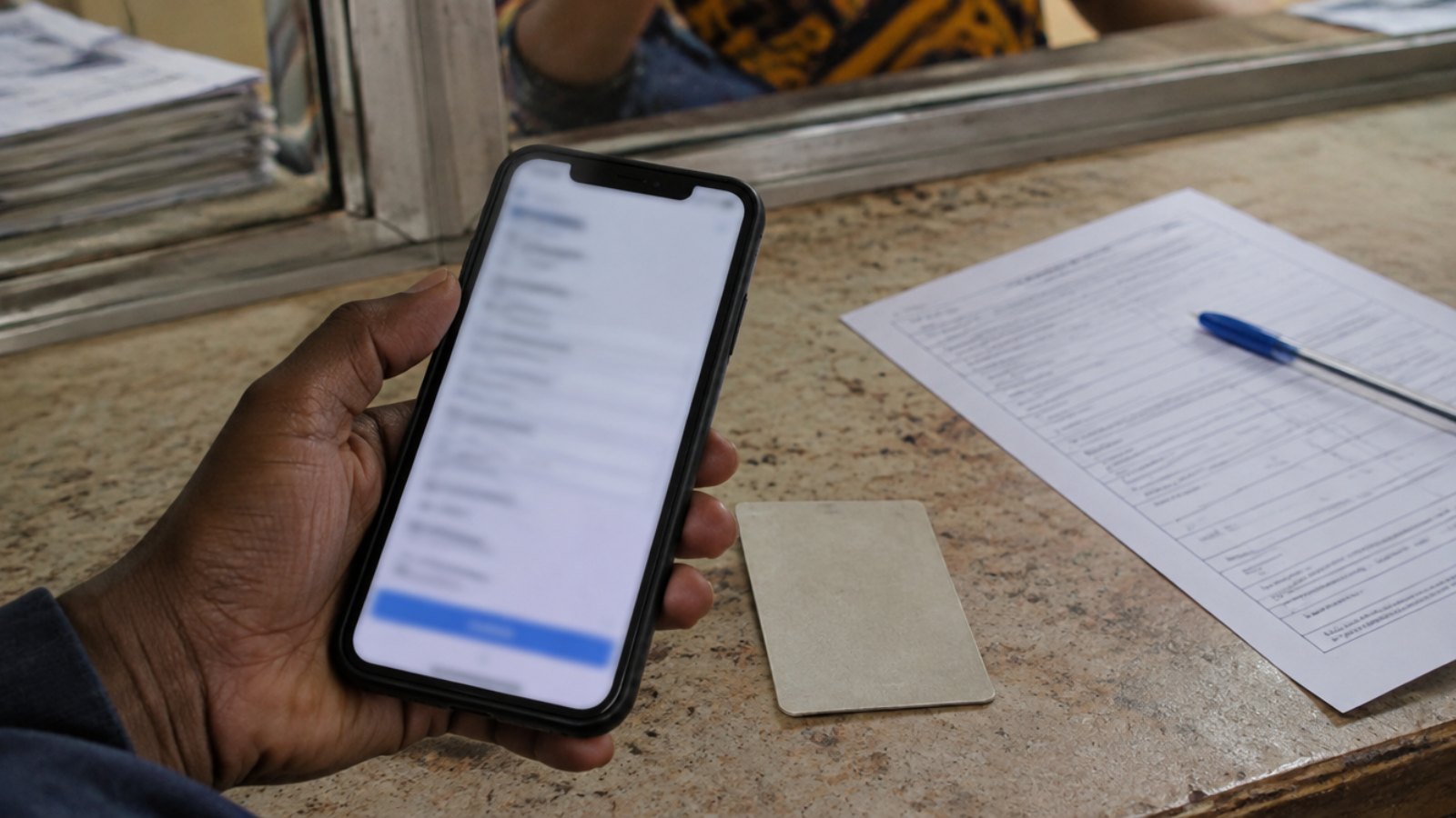 Hand holding a smartphone showing an online form next to a printed administrative form