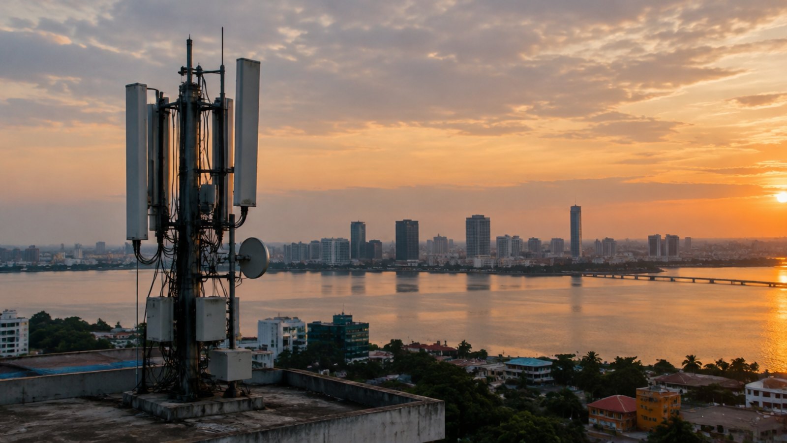 Telecom antenna on a rooftop with the Abidjan lagoon and skyline at dusk